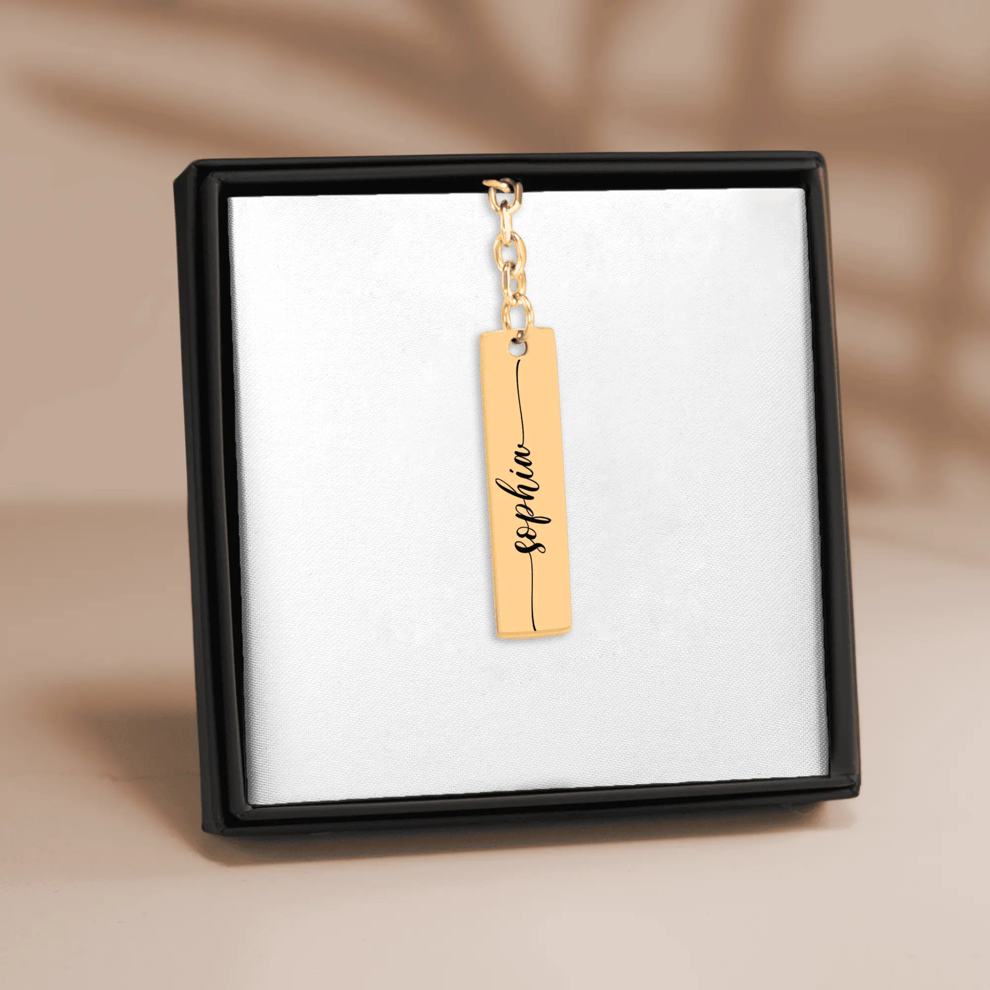 Custom name bar keychain in gold finish featuring personalized name 'Sophie' on a display.