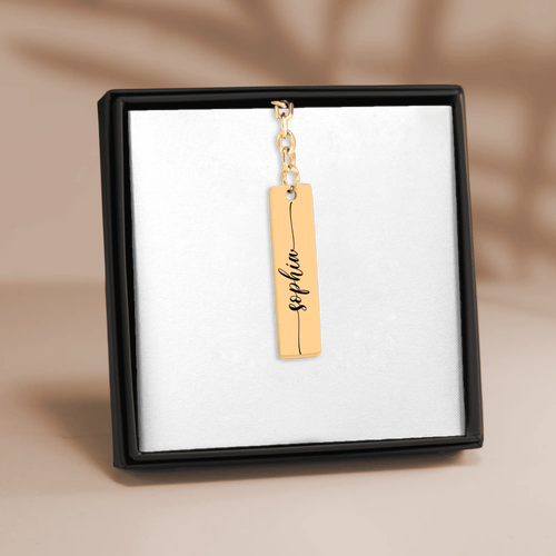 Custom name bar keychain in gold finish featuring personalized name 'Sophie' on a display.